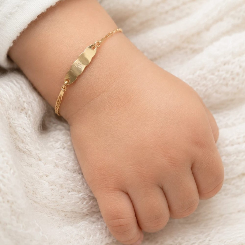 Esclava de oro con chapa nube lisa puesta en la muñeca de un bebé