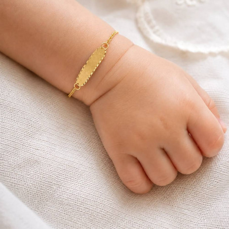 Esclava de oro con chapa nube arenada puesta en la muñeca de un bebé