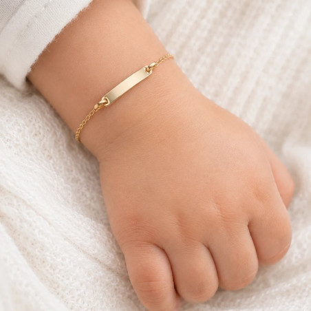 Esclava de oro con chapa rectangular lisa puesta en la muñeca de un bebé